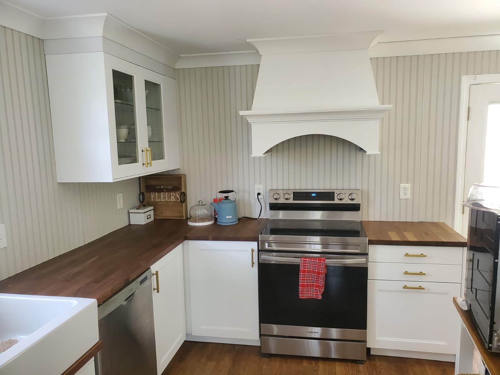 White kitchen with a custom range hood and glass-front upper cabinets