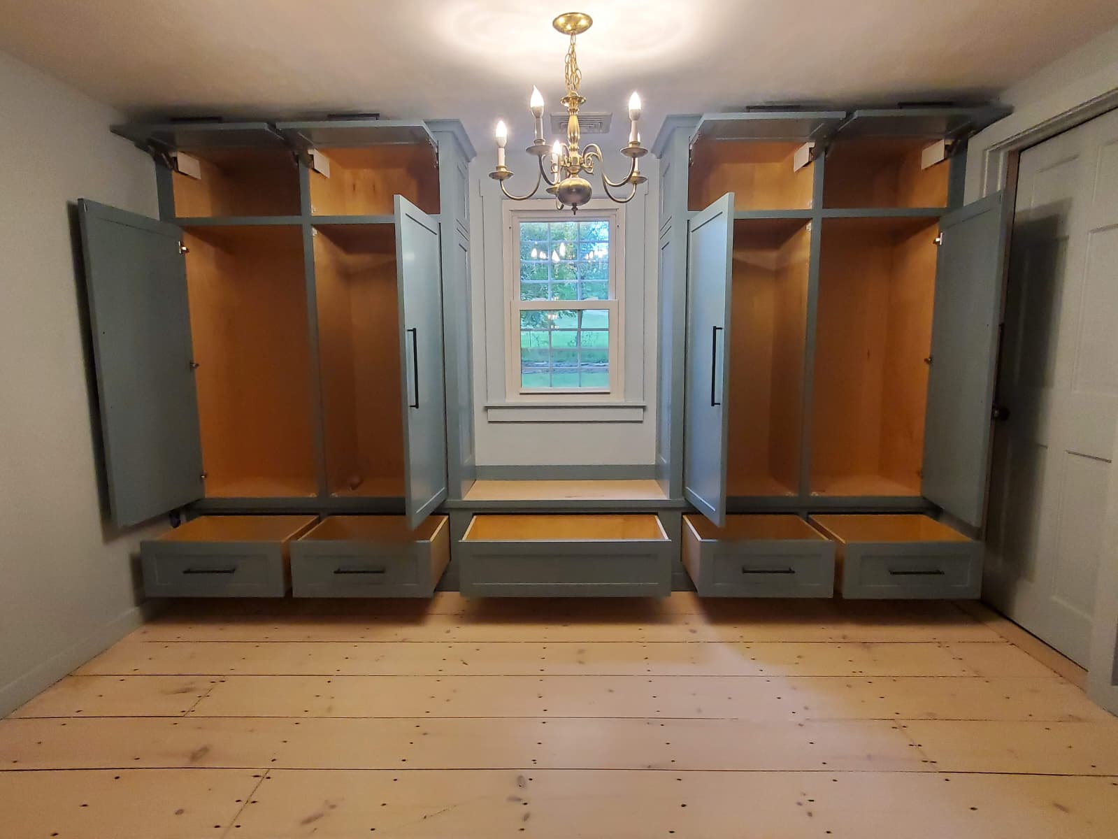 Mudroom lockers with open doors, drawers, and a bench under a window