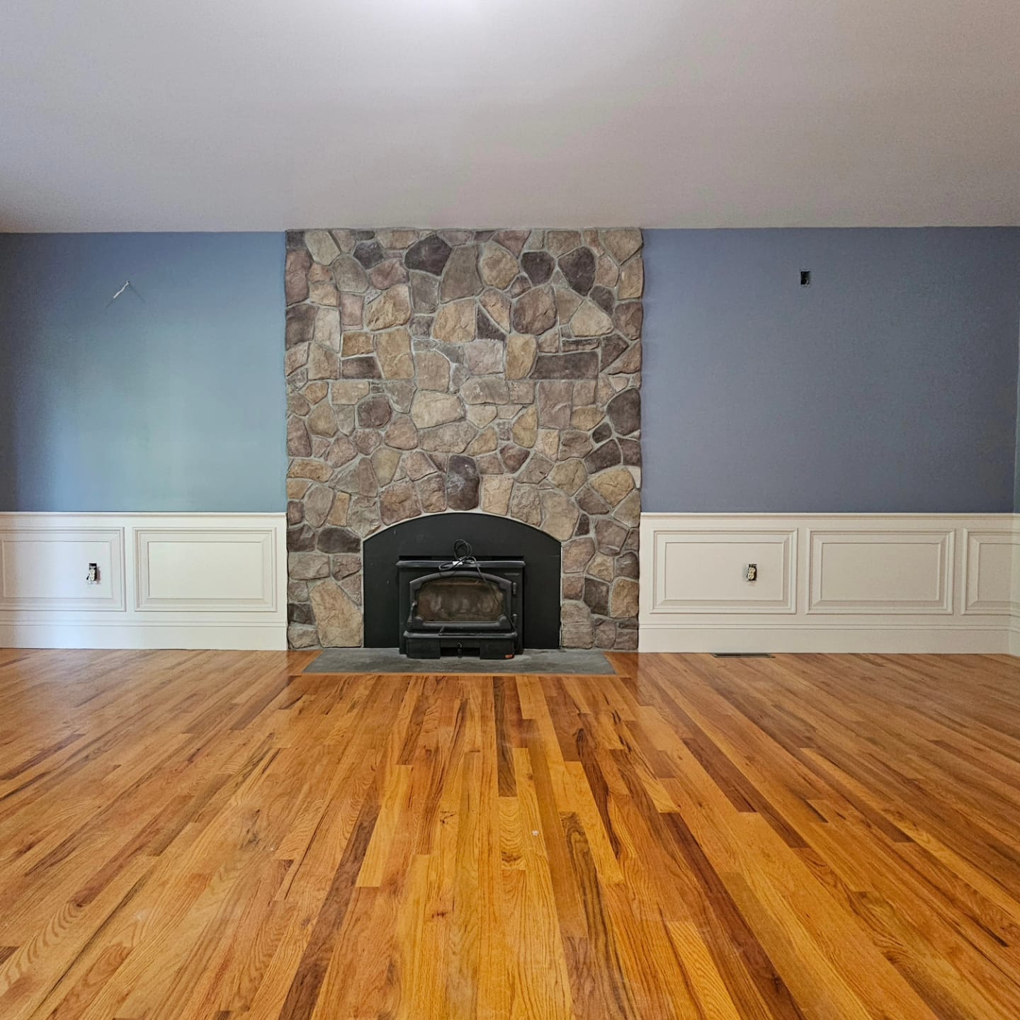 Raised-panel wainscoting around a stone fireplace