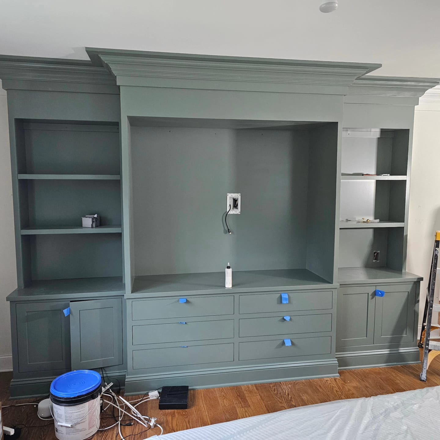 Sage green built-in media wall with crown molding and inset drawers
