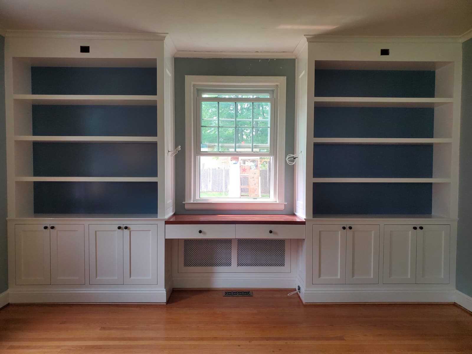 White built-in bookshelves flanking a window desk