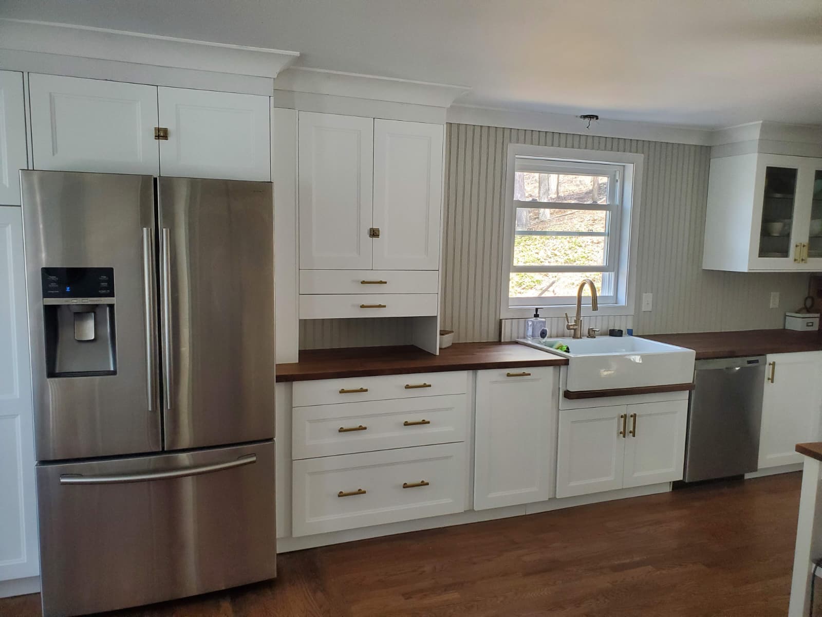 White shaker kitchen with walnut counters and a farmhouse sink